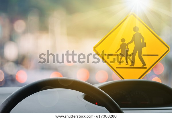 School zone warning sign and inside car view
,steering wheel on blur traffic road with colorful bokeh light
abstract background. Copy space of transportation and travel
concept. Vintage tone
color.