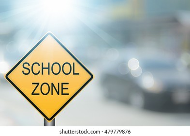 School Zone Warning Sign On Blur Traffic Road With Colorful Bokeh Light Abstract Background. Copy Space Of Transportation And Travel Concept. Vintage Tone Color Style.