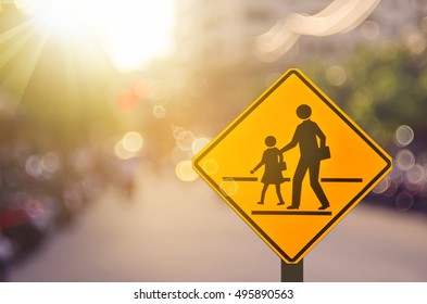 School Zone Warning Sign On Blur Traffic Road With Colorful Bokeh Light Abstract Background. Copy Space Of Transportation And Travel Concept. Vintage Tone Filter Color Style.