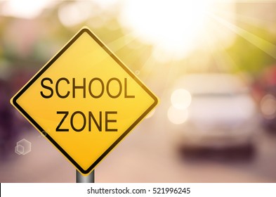 School Zone Warning Sign On Blur Traffic Road With Colorful Bokeh Light Abstract Background. Copy Space Of Transportation And Travel Concept. Vintage Tone Filter Color Style.