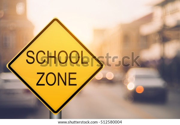 School zone\
warning sign on blur traffic road with colorful bokeh light\
abstract background. Copy space of transportation and travel\
concept. Vintage tone filter color\
style.