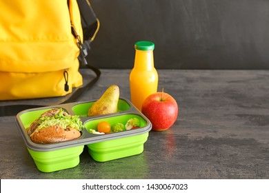 Schoolbag And Lunch Box With Tasty Food On Table