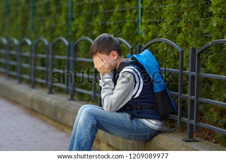 Schoolboy crying in the yard of the school. Negative emotion.