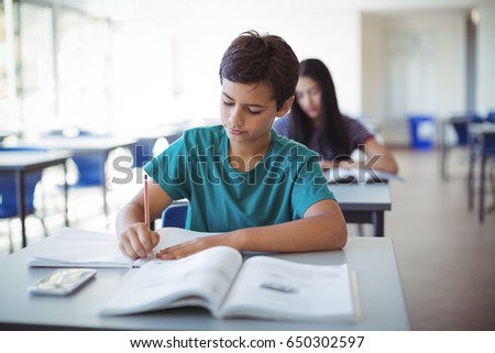 Schoolboy doing homework in classroom at school