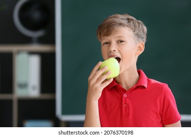 Schoolboy eating apple against blurred background in school - Powered by Shutterstock