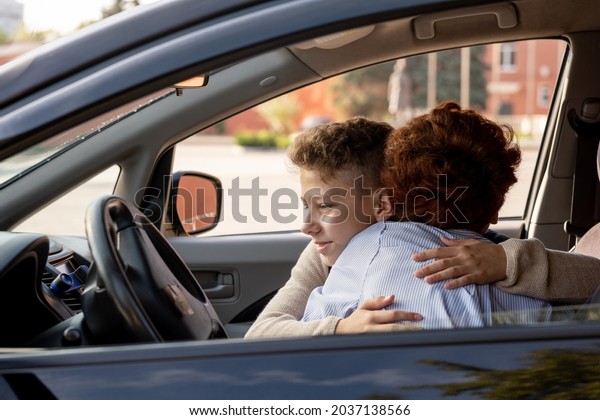 Schoolboy embracing his mother in the car before\
going to school in the\
morning