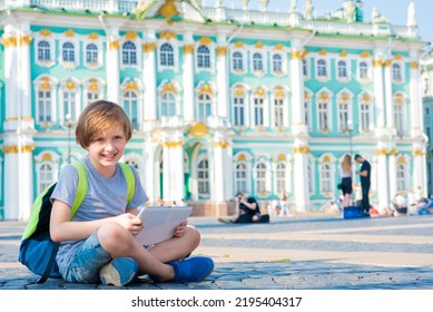 Schoolboy Is Engaged Using A Tablet Outside. The Child Watches Lectures From Anywhere In The World, Learns While Traveling Online, Remotely, In Correspondence Or Family Education Via The Internet.