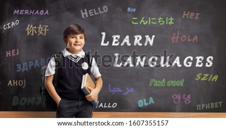 Schoolboy in front of a blackboard with hello written in different languages and text learn languages