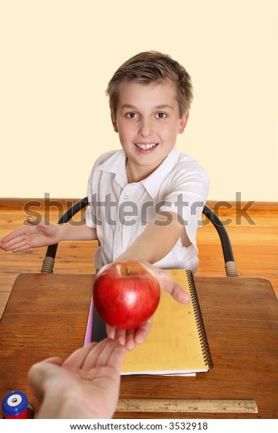 A schoolboy\
hands his teacher a red\
apple.