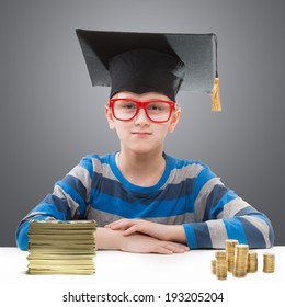 Schoolboy in a mortar board with piles of money at the table in front of him 