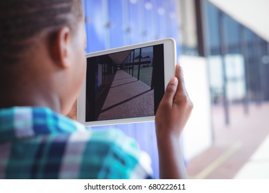 Schoolboy photographing corridor through digital tablet while standing at school during sunny day - Powered by Shutterstock