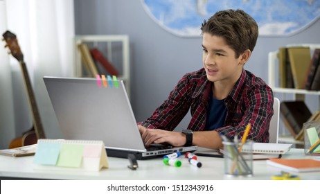 Schoolboy playing online game on laptop at home sitting table, teenage free time - Powered by Shutterstock