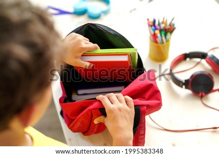 schoolboy puts office supplies in a backpack. Preparing for school. Back to school. Self-assembly of a school backpack. Close-up [[stock_photo]] © 