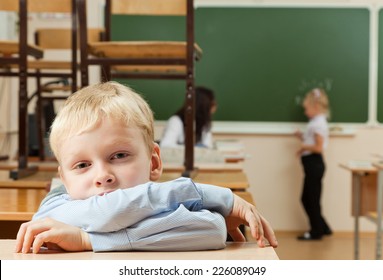 Schoolboy Is Sitting In The Half Empty Classroom After Classes. He Is Bored.