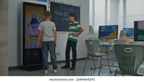 Schoolboy Uses Interactive Digital Screen, Talks Classmate. Boys Study STEM Classroom. Concept Of Integrating Educational Technologies, Social-emotional Learning Into Modern Education. Dolly Shot.