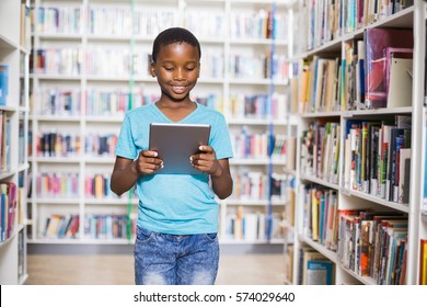 Schoolboy Using Digital Tablet In Library At School