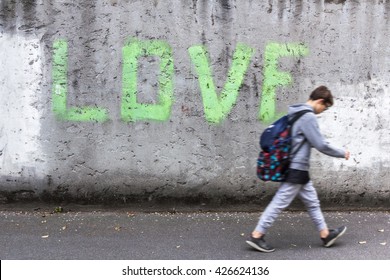 A schoolboy walking down the street with head bowed; on the wall stands the inscription "LOVE".