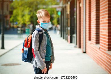 Schoolboy Wearing Face Mask During Epidemic. Back To School Concept. Cute Boy Outside At School Having Good Time. Safety Mask To Coronavirus Prevention. Kid With Backpack Going To School. Education.