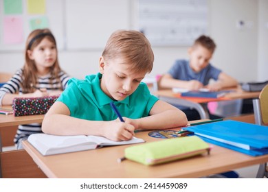 Schoolboy writing in exercise book in class - Powered by Shutterstock