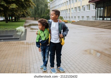 Schoolboys With Backpacks. Two African American Boys Next To The School. Back To The School Concept. Kids Standing Outside And Happy To Meet Each Others. Happy Black Children. First Day Of School