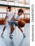 Schoolboys having fun while playing basketball during PE class at school.