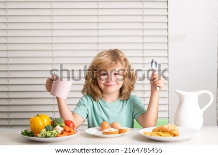 Schoolchild eating breakfast before school. Portrait of little teen child sit at desk at home kitchen have delicious tasty nutritious breakfast.