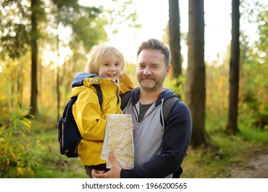 Schoolchild And His Mature Father Hiking Together And Exploring Nature. Boy With Dad Spend Quality Family Time Together In Sunny Forest. Adventure, Scouting, Orienteering And Hiking Tourism For Kids.