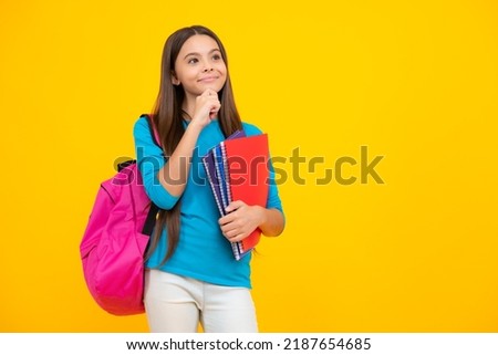Schoolchild, teenage student girl hold book on yellow isolated studio background. School and education concept. Back to school. Thinking face, thoughtful emotions of teenager girl.
