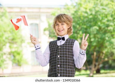 Schoolchildren boy waving the flag of Canada against the background of the college. Education in Canada.
