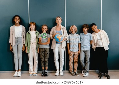 Schoolchildren classmates kids pupils students standing with teacher holding globe and recycling sign at geography school lesson class. Eco-activists. Environment protection. - Powered by Shutterstock