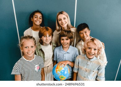 Schoolchildren classmates kids pupils students standing with teacher holding globe at geography school lesson class. Eco-activists. Environment protection.Traveling concept. Multy-ethnic society group - Powered by Shutterstock