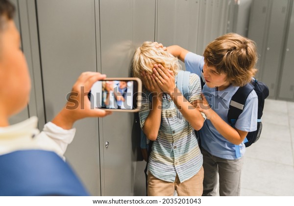 Schoolchildren\
cruel boys filming on the phone torturing bullying their classmate\
in school hall. Puberty difficult\
age