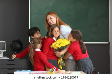 Schoolchildren greeting their teacher in classroom