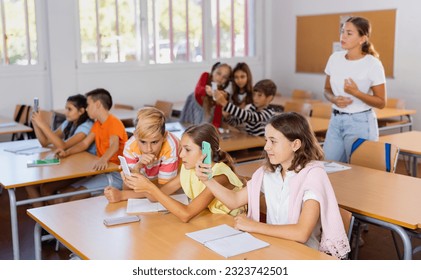 Schoolchildren use mobile phones at the lesson in the classroom