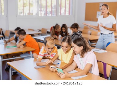 Schoolchildren use mobile phones at the lesson in the classroom - Powered by Shutterstock