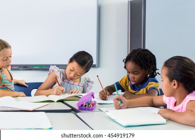 Schoolchildren writing on books in classroom - Shutterstock ID 454919179