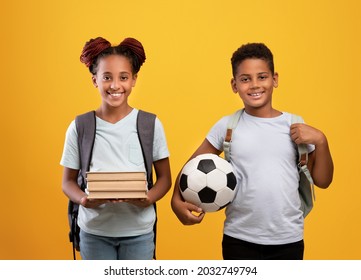Schoolers lifestyle, kids education and entertainment concept. Happy preteen black brother and sister with backpacks, books and soccer ball cheerfully posing on yellow studio background