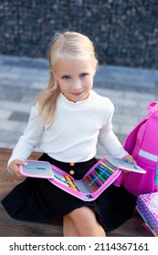 Schoolgirl With A Backpack, Pencil Case And Books. Girl Sits On The Bench. Pupil In School Uniform. Back To School, Young Girl Ready For Class.