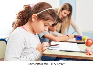 Schoolgirl chatting on her smartphone in class at elementary school