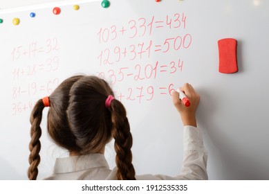 Schoolgirl counting mathematical equations on the board. Secondary school learner is good at math, doing the task easily