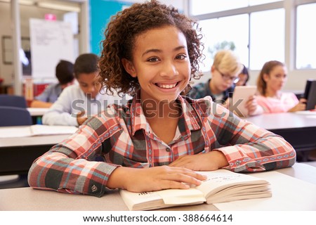 Schoolgirl at desk in elementary school looking to camera