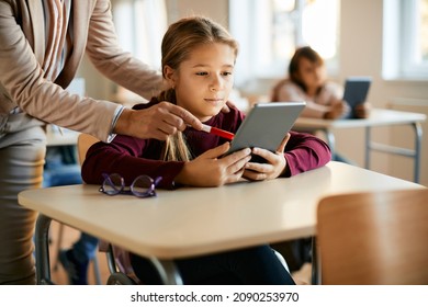 Schoolgirl e-learning on digital tablet with help of a teacher in the classroom. - Powered by Shutterstock