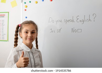 Schoolgirl English Learner Showing Thumbs Up, Standing Near The Board With Inscription Do You Speak English? And Positive Answer To It. Learning International Language