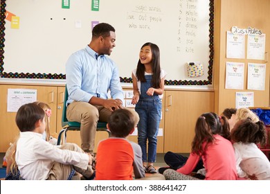 Schoolgirl At Front Of Elementary Class Talking With Teacher