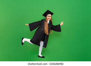 A Schoolgirl In Full Growth. A Student Runs To School In A School Uniform. A Graduate In A Master's Gown And A Cap On An Isolated Green Background. A Girl With Glasses.