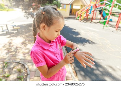 A schoolgirl girl presses the power button on a smart watch. Children online. Communication with parents. Convenient trendy gadgets. Watch with phone function.
 - Powered by Shutterstock