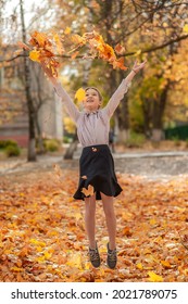 Schoolgirl Girl In Strict School Clothes Throws Up Autumn Maple Leaves