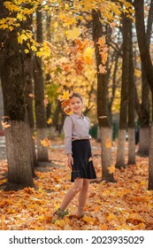 Schoolgirl Girl In Strict School Clothes Throws Up Autumn Maple Leaves