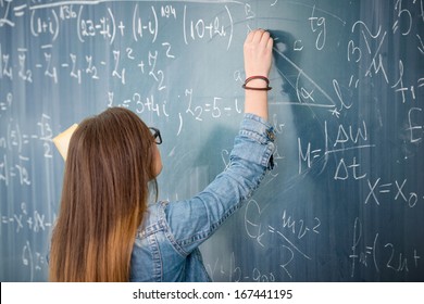 Schoolgirl with glasses solving math problem on blackboard - Powered by Shutterstock