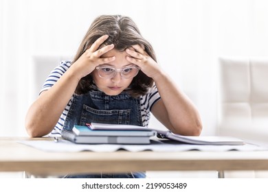 Schoolgirl In Glasses Tries To Comprehend Study Materials Holding Her Head By Both Hands.